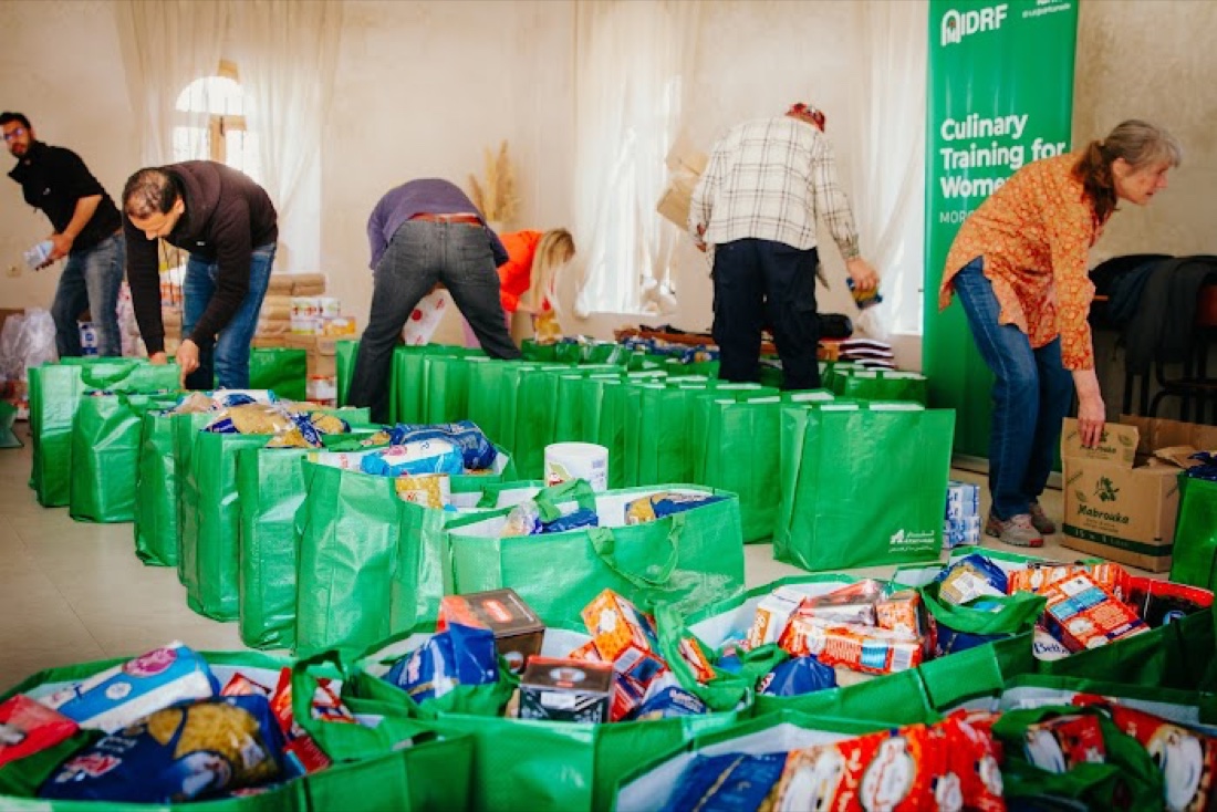 Amal volunteers packing relief food bags beneath the Amal banner