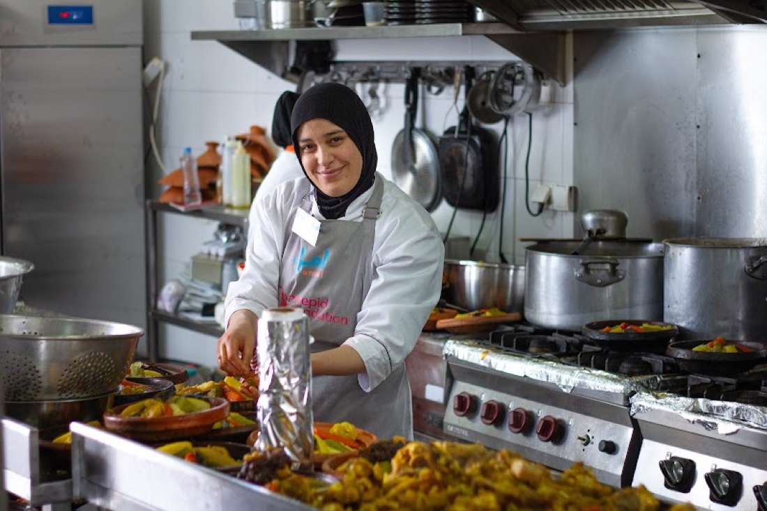 A proud Amal trainee cooking a large batch in the kitchen