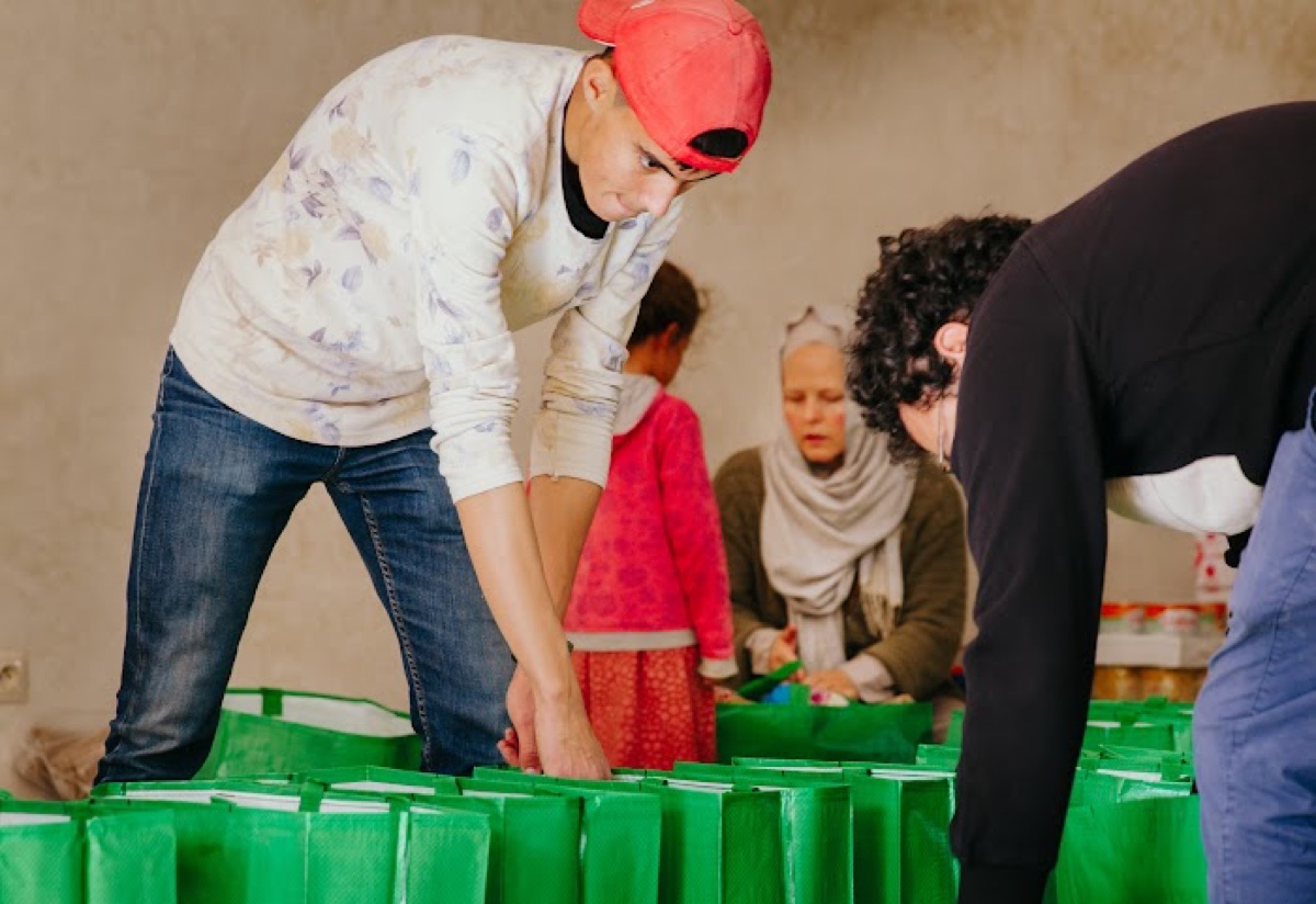 Volunteers packing green charity food parcels for Ramadan distribution